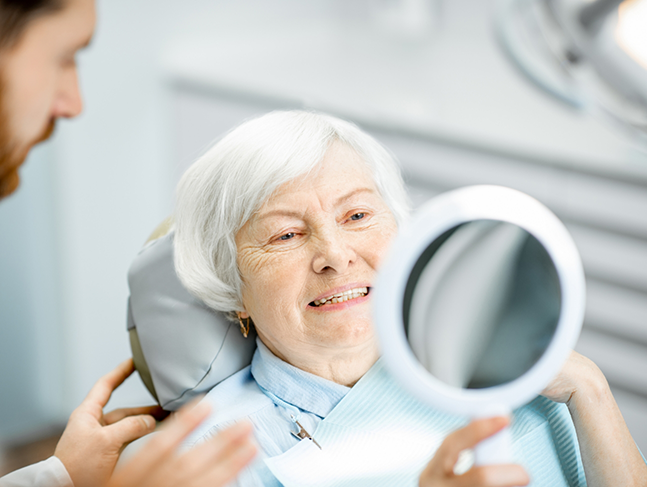Senior dental patient admiring her smile in a mirror