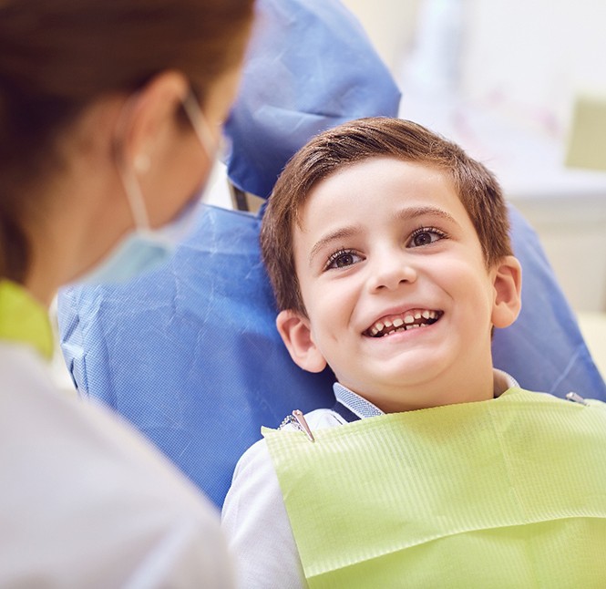 Little boy in dental chair smiling at dentist
