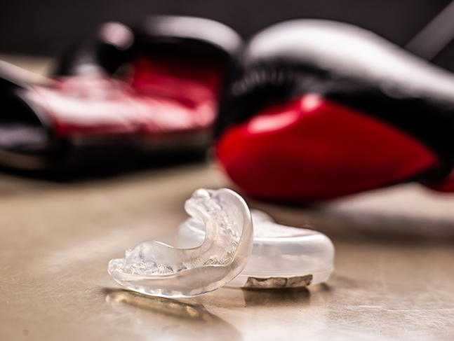Clear mouthguard next to two red boxing gloves