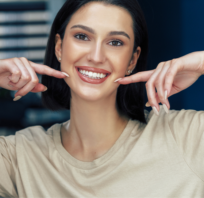 Woman pointing to her flawless smile after cosmetic dentistry in San Antonio