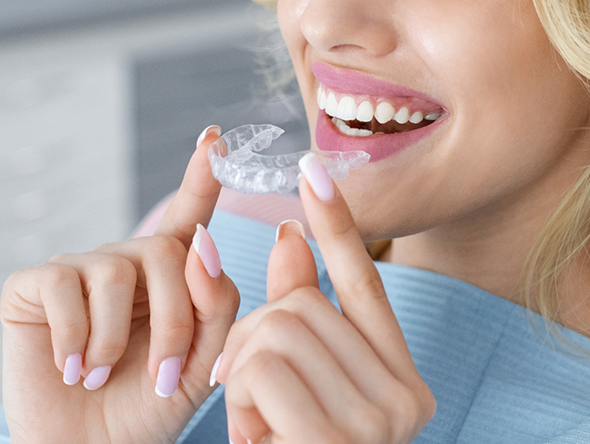 Blonde woman placing Invisalign over her teeth