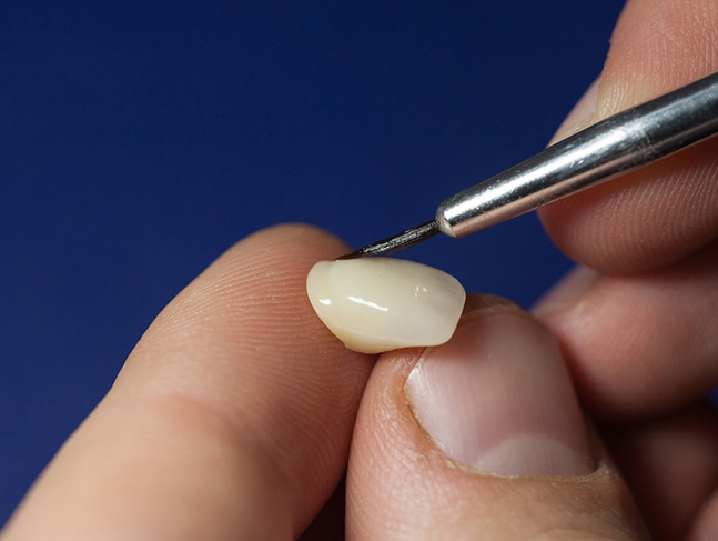 Person applying adhesive material to a veneer