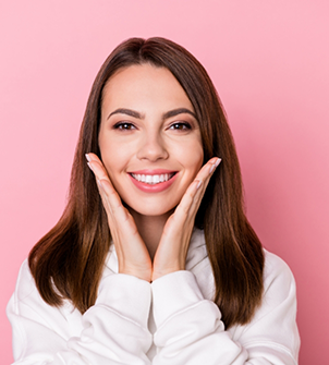 Smiling brunette woman framing her face with her hands