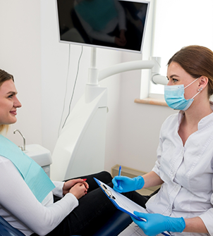 Dentist listening to a patient while writing on a clipboard