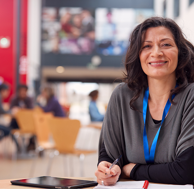 Teacher at her classroom desk smiling with dental crowns in San Antonio