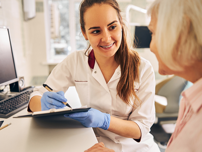 Dental team member listening to a patient and writing on a clipboard
