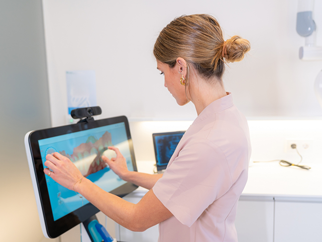 Dental team member touching a screen showing a digital impression of a patient's teeth
