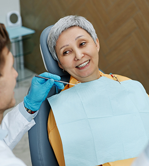 Woman in the dental chair smiling at her dentist