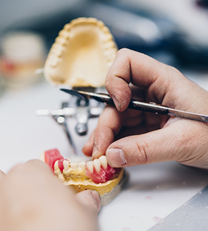 Dental lab worker adjusting a denture