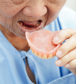 Senior woman placing her denture in her mouth