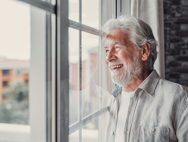 Smiling senior man looking out of a window