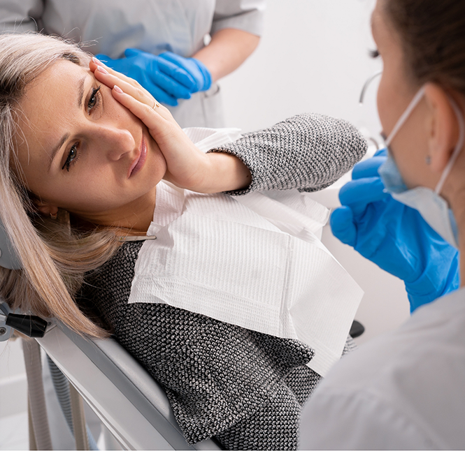 Woman holding her cheek in pain while talking to an emergency dentist in San Antonio
