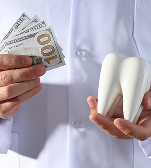 Person holding dollar bills and a model of a tooth