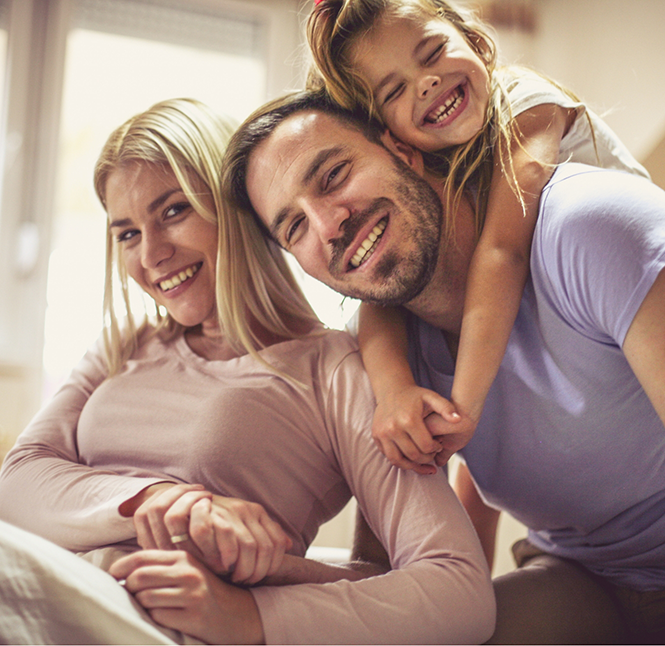 Parents and their young daughter smiling after seeing a family dentist in San Antonio