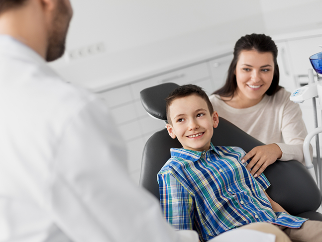 Young boy in the dental chair smiling at his family dentist