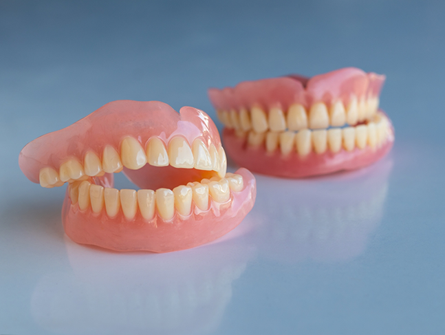 Two sets of full dentures sitting on a flat surface