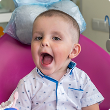 Toddler in the dental chair opening their mouth wide