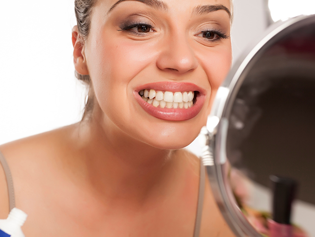 Woman looking at her teeth in a mirror