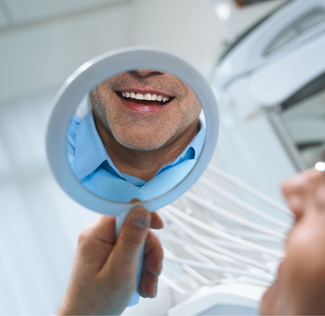 Dental patient smiling at his reflection with tooth-colored fillings in San Antonio