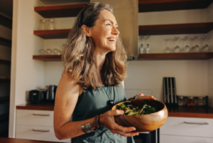 a smiling woman holding a bowl of salad