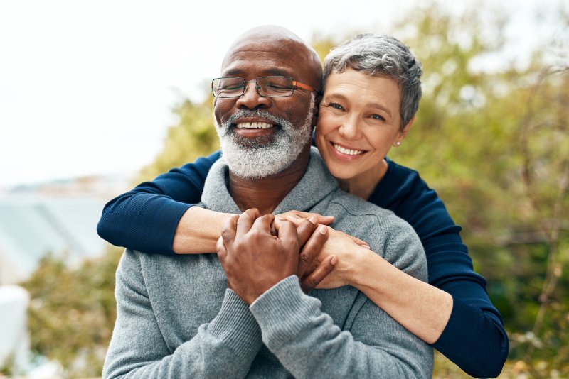 Older patient smiling with partner after cosmetic dentistry